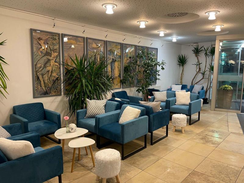 Moderne Hotellobby mit blauen Sesseln, weißen Kissen und großen Pflanzen