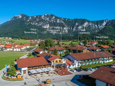 Mountain village with traditional buildings in front of forested mountain panorama under blue sky