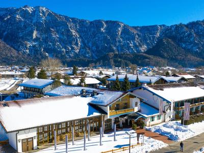 Snow-covered hotel village with mountainous backdrop under clear sky.