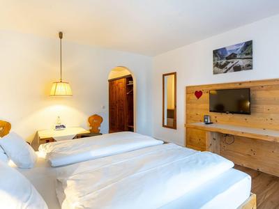 Cozy hotel room with two beds, wooden decor, and a wall-mounted TV.