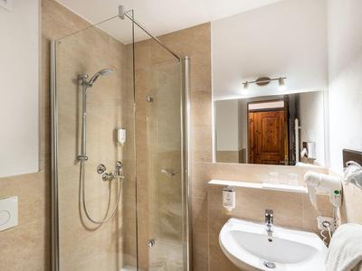 Modern bathroom with shower, sink, mirror, and towels in neutral colors.