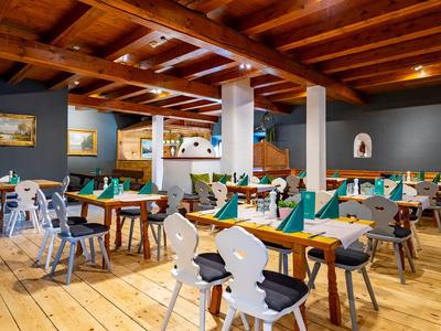 Acogedor comedor con techo de vigas de madera, suelo de madera y sillas variadas en las mesas.