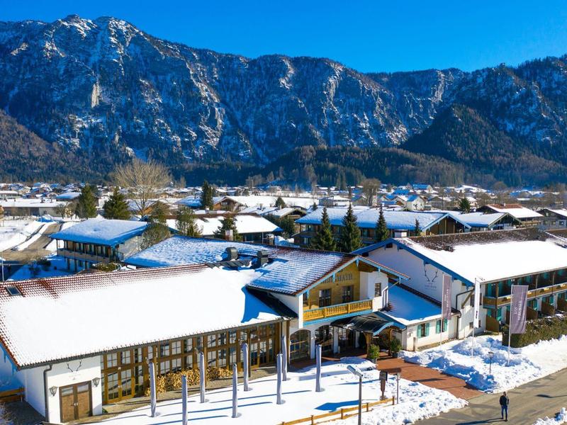 Snow-covered hotel village with mountainous backdrop under clear sky.