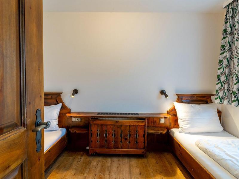 A simple room with two single beds, a nightstand between them, and leaf-patterned curtains.