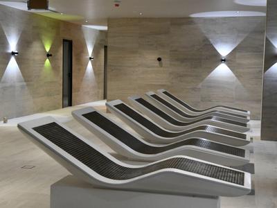 Sala de relax moderna con tumbonas curvas y luz de pared brillante y minimalista.