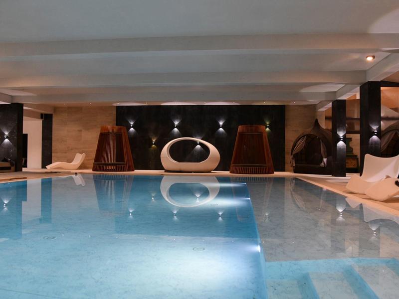 Vista interior de una piscina tranquila con tumbonas y elementos decorativos al fondo.