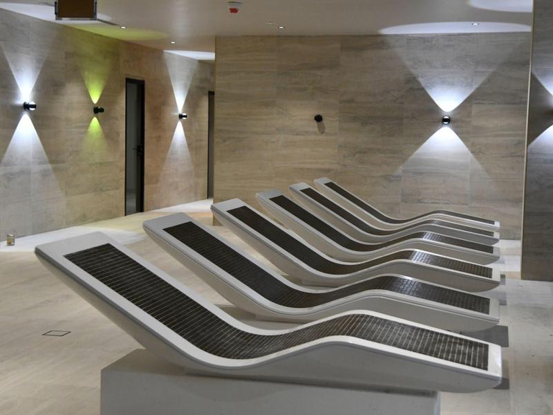 Sala de relax moderna con tumbonas curvas y luz de pared brillante y minimalista.