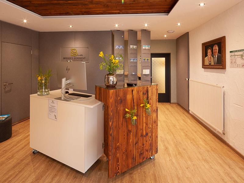 Moderner Hotel- oder Empfangsbereich mit Holzakzenten, Blumen und minimalistischer Einrichtung.