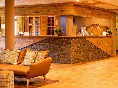 Pohodlná hotelová recepce s dřevěným nábytkem a kamenným obkladem u přepážky.