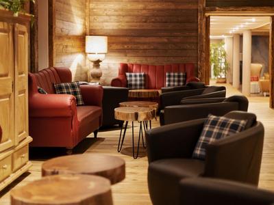 Pohodlný hotelový salon s pohodlnými křesly, dřevěnou podlahou a teplým osvětlením.