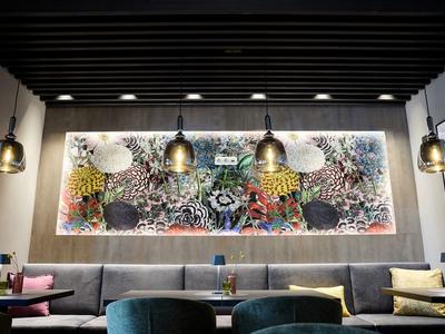 Moderner Hotel-Loungebereich mit bunter abstrakter Wandkunst und hängenden Lampen.