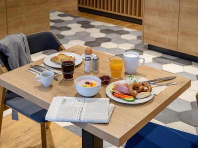 Tisch mit vielfältigem Frühstück, Getränken und einer Zeitung in modernem Restaurant.