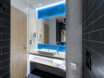 Modernes Badezimmer mit großem Spiegel, weißem Waschbecken und blauer LED-Beleuchtung.