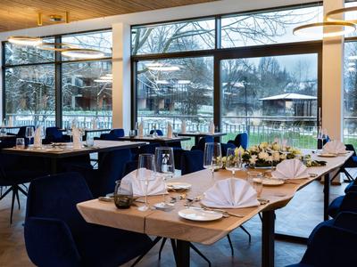 Elegantes Restaurant mit großen Fenstern, gedeckten Tischen und Blick auf verschneite Außenbereiche.