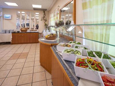 Area buffet con ciotole di insalate fresche e verdure in una sala da pranzo luminosa.