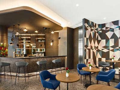 Moderne Hotelbar mit hochmodernen Stühlen, Tischen und einer geometrischen Wanddekoration.