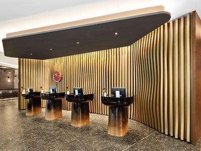 Moderne Rezeption mit schwarzen runden Tresen und goldfarbenen vertikalen Wandpaneelen in hellem Raum.