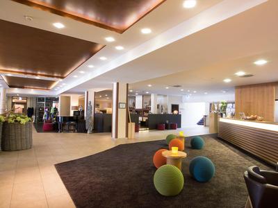 Moderne Hotel-Lobby mit Sitzmöbeln, Teppichen und heller Beleuchtung.