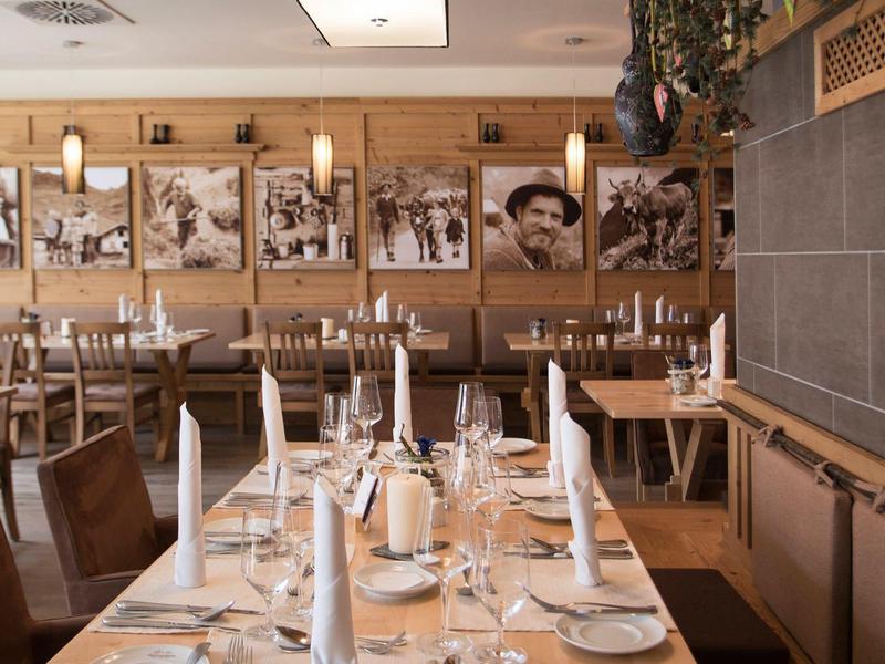 Modern eingerichtetes Restaurant mit Holzwänden, gedeckten Tischen und Schwarz-Weiß-Fotos an der Wand.