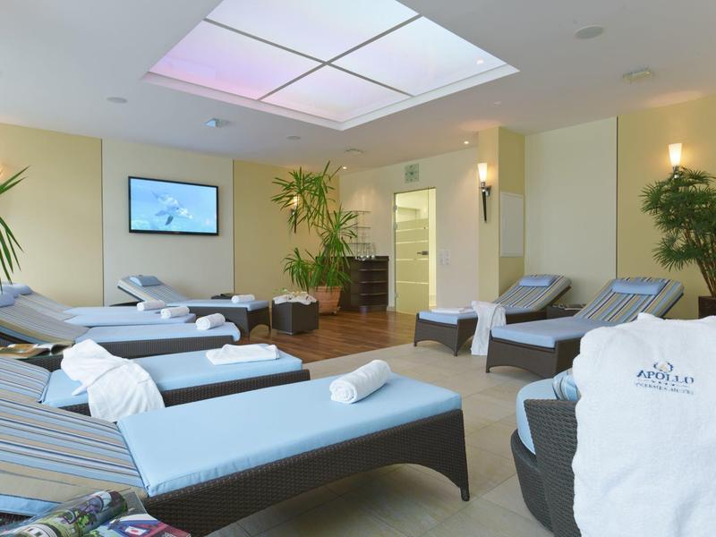 Stanza benessere luminosa con lettini, asciugamani e piante verdi.