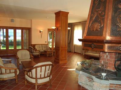 Gemütlicher Wohnbereich mit Sesseln, Kamin und Zugang zu einer Terrasse mit Blick ins Freie.