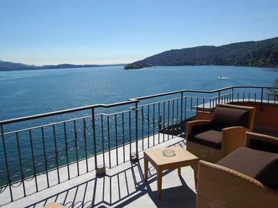 Balkon mit Sitzmöbeln und Blick auf das Meer und die Berge bei klarem Himmel.