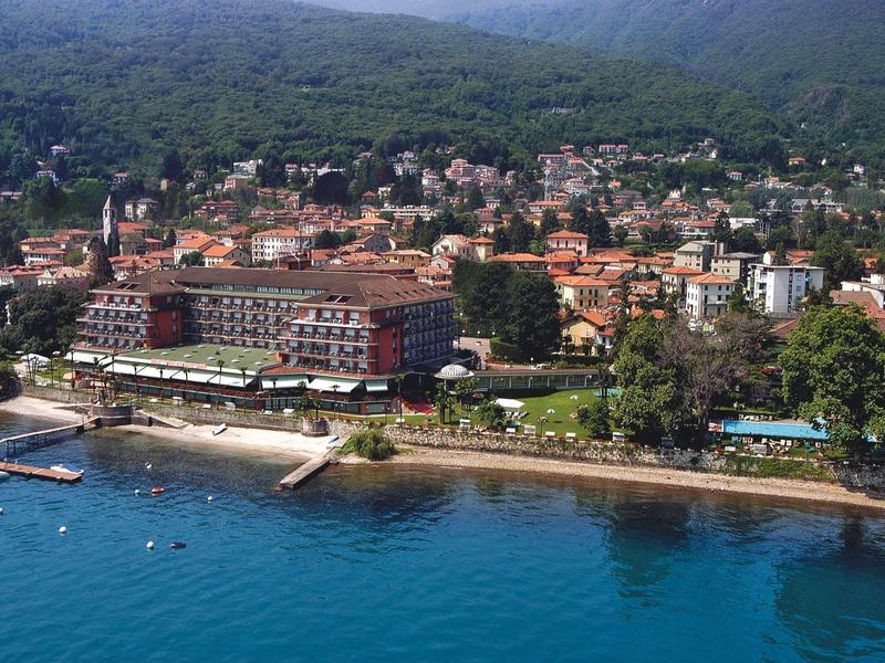 Kuststad met hotels, strand en beboste heuvel op de achtergrond.