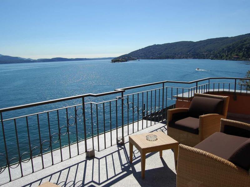 Balkon met twee fauteuils en tafel met uitzicht op de zee en nabijgelegen heuvels.