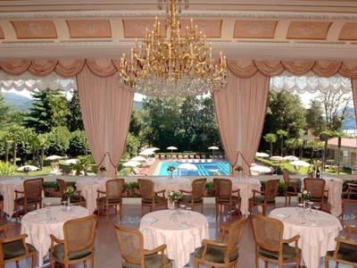 Eleganter Speisesaal mit runden Tischen und Blick auf Swimmingpool und Garten