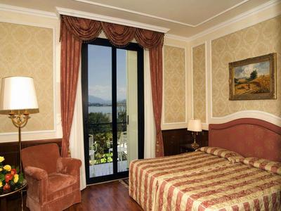 Gemütliches Hotelzimmer mit Doppelbett, Sessel, Lampen und Balkon mit Aussicht.