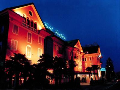 Großes Hotelgebäude bei Nacht mit orangefarbener Beleuchtung und blauem Schriftzug "Hotel Imperial".