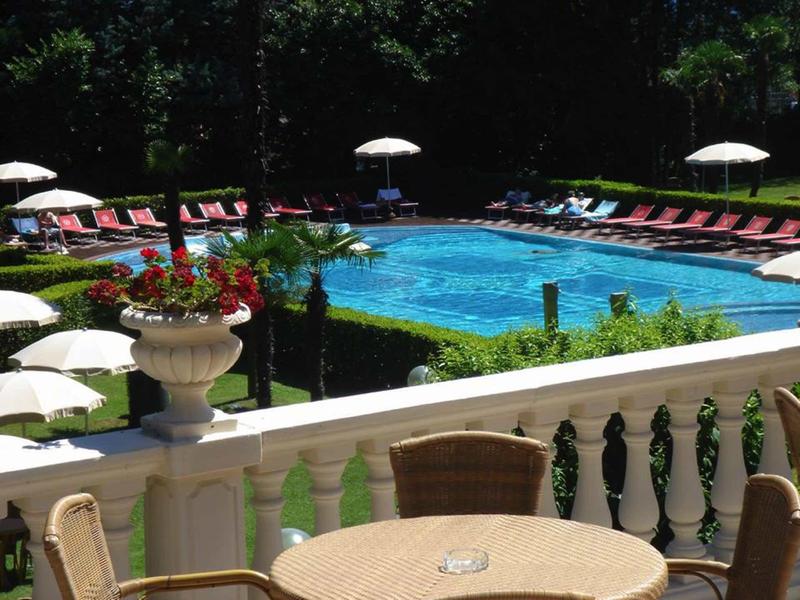 Pool area with lounge chairs, umbrellas, and white railing in the foreground