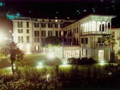 Beleuchtetes Hotelgebäude mit Garten und Palmen bei Nacht