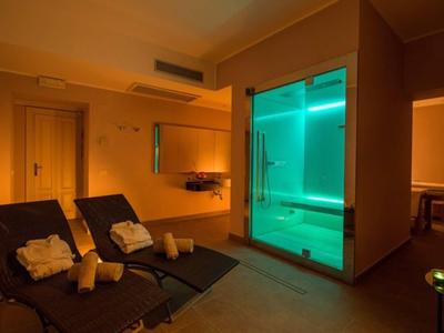 Area benessere accogliente con lettini e bagno turco illuminato da luce calda.