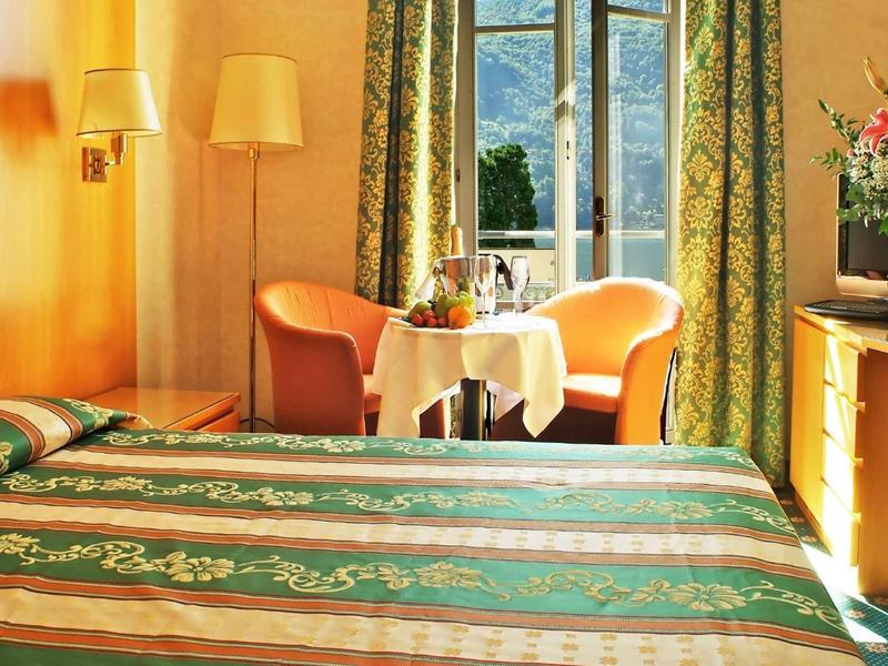 Camera d'hotel accogliente con due poltrone, un tavolo e un letto decorativo.