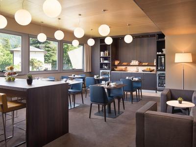 Modern gestalteter Hotel-Loungebereich mit Sitzgelegenheiten, Bar und großen Fenstern.