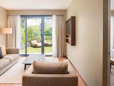 Helle Hotel-Lounge mit Sofa, Stuhl, Teppich und Blick auf Garten durch Glasfenster