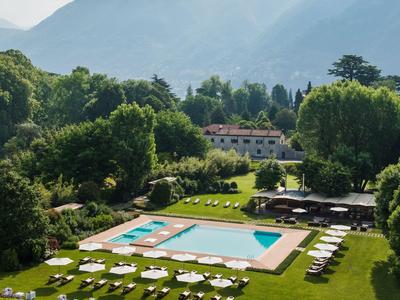 Luxuriöser Poolbereich in einem Garten mit Liegestühlen und Bergen im Hintergrund