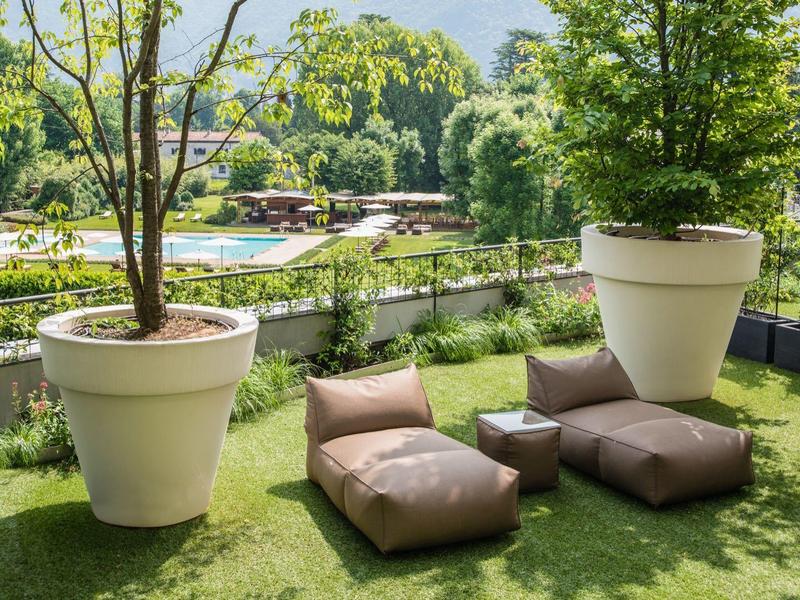 Gezellige zitplaatsen op een terras met uitzicht op bomen en gebouwen.