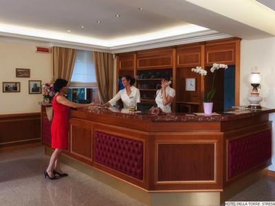 Hotelrezeption mit Empfangspersonal und Gast, klassische Holztheke und warme Beleuchtung.