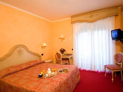 Gemütliches Hotelzimmer mit Doppelbett, Schreibtisch, Fernseher und Balkon mit Vorhängen