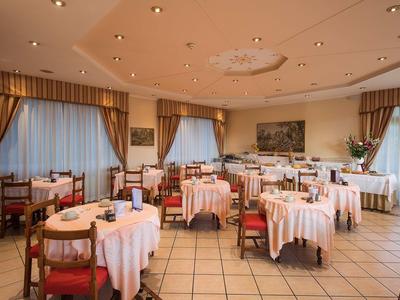 Elegantes Speisezimmer mit weiß gedeckten Tischen und roten Stühlen in einem Hotel.