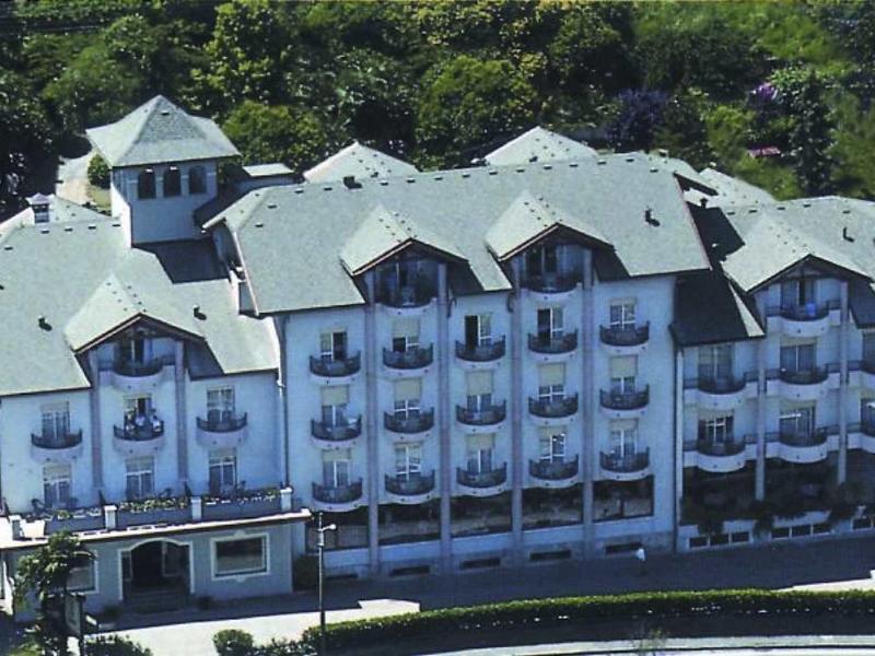 Grande edificio dell'hotel con facciate bianche e molte finestre, circondato da alberi.