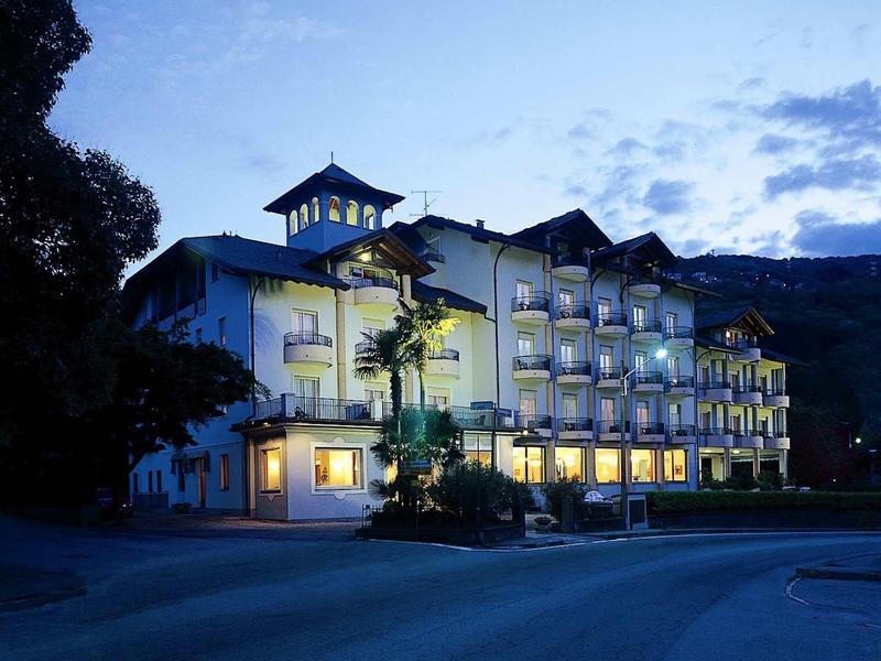 Edificio dell'hotel illuminato la sera con montagne sullo sfondo.
