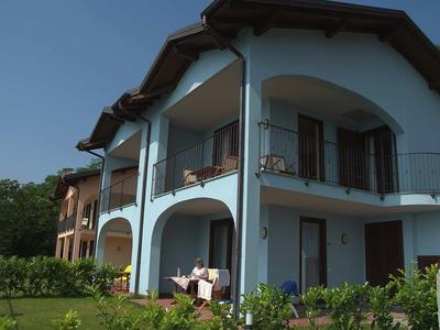 Modernes zweistöckiges Ferienhaus mit Balkon und Garten bei klarem Himmel.