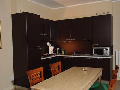 Moderne Hotelküche mit dunklen Schränken und einem Esstisch mit Stühlen