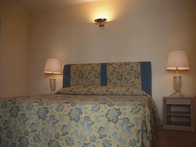 Gemütliches Hotelzimmer mit großem Bett, floraler Bettwäsche und zwei Nachttischen mit Lampen.