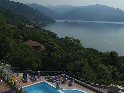 Schwimmbad mit blauen und gelben Liegestühlen, umgeben von Hügeln und einem großen See im Hintergrund.