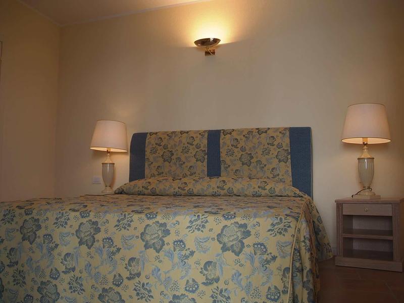 Gemütliches Schlafzimmer mit Doppelbett, Blumenbettwäsche, zwei Nachttischen und warmem Licht.