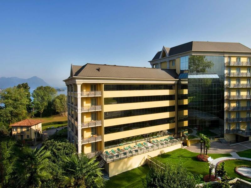 Modern hotel with glass facade and surrounding garden under clear sky